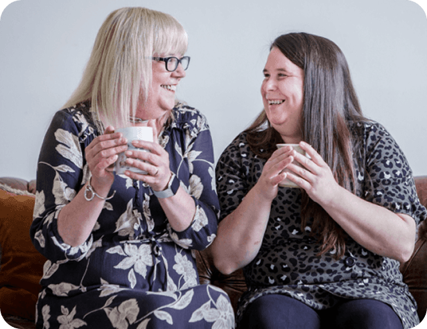 Two people smiling and chatting on a sofa